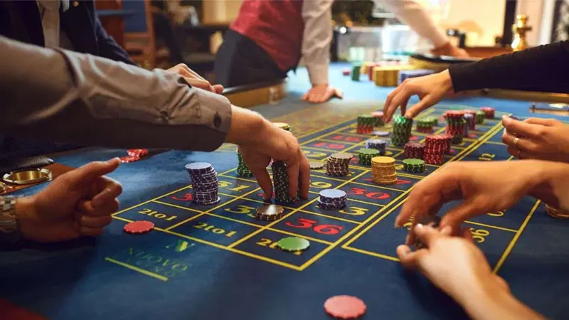 Hands placing casino chips on red and black sections of roulette table